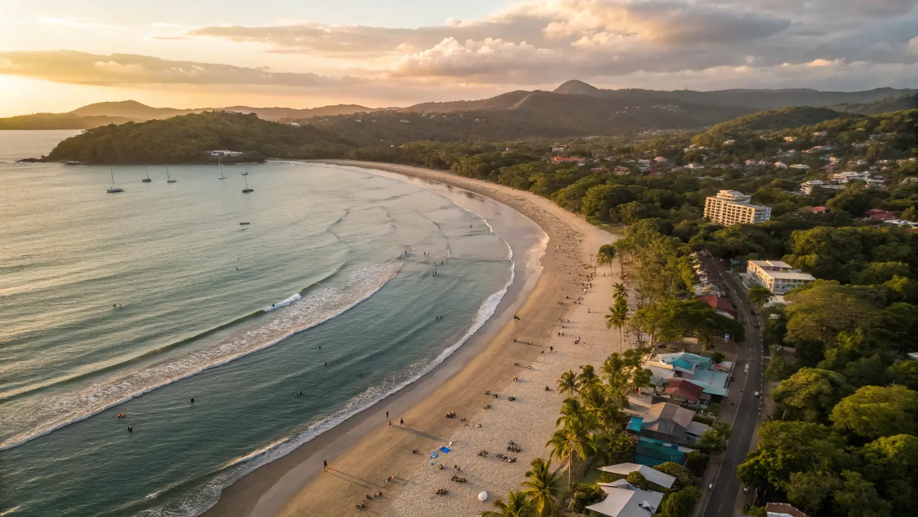 Aerial view of Tamarindo Beach at sunset with golden sands, turquoise waters, and surrounding lush landscape