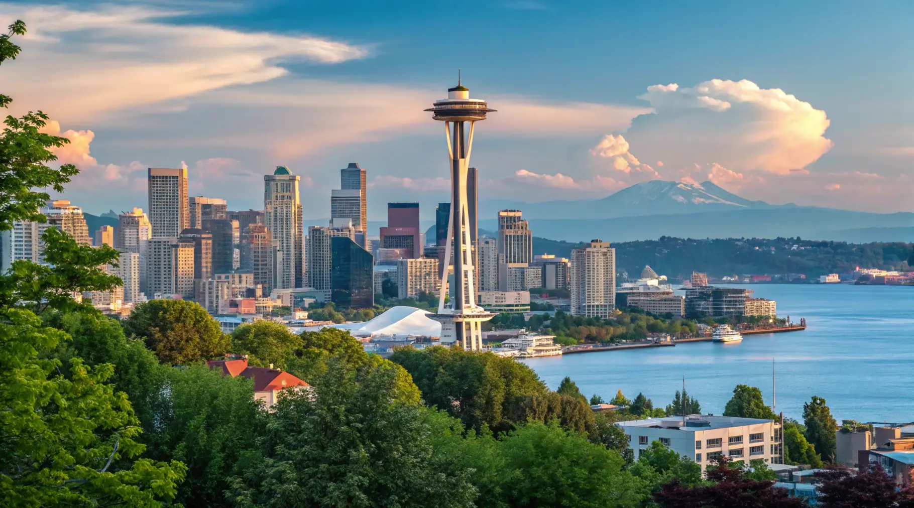 A panoramic view of Seattle's skyline with the Space Needle prominently displayed, surrounded by trees and the waterfront, representing Seattle travel.