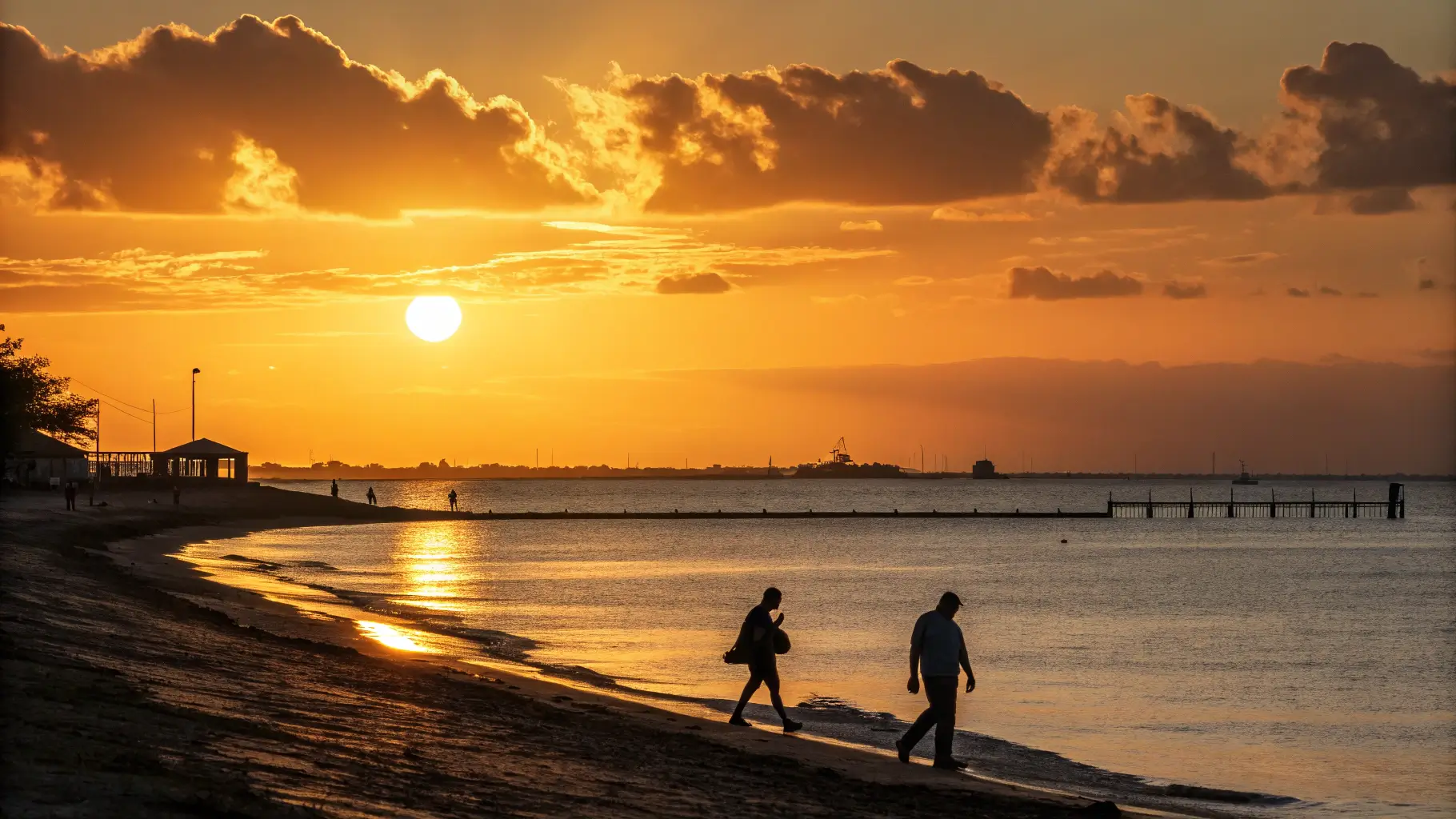 Sunset over Rockport Beach, Texas, with silhouettes of people walking along the shore.