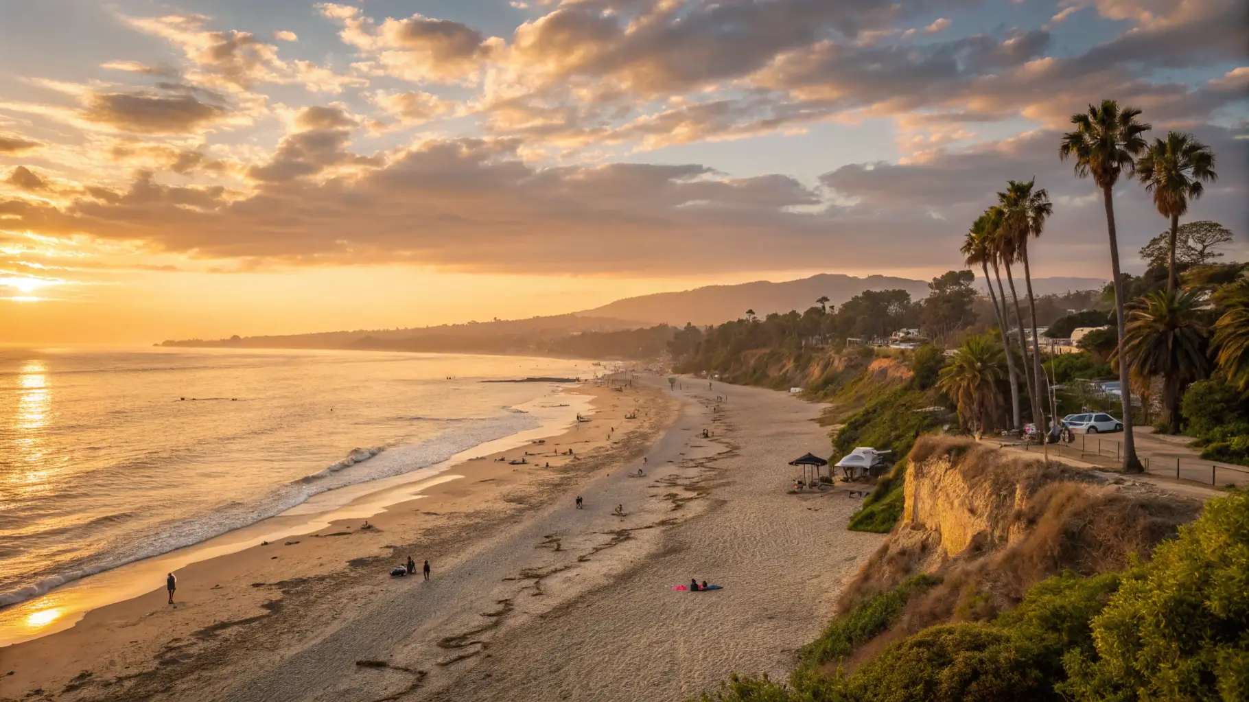 A beautiful sunset over Butterfly Beach, with people relaxing on the sand and waves gently lapping at the shore.